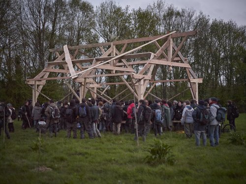 Группа людей возле каркаса дома